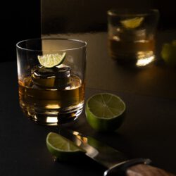 clear drinking glass with yellow liquid and sliced lime