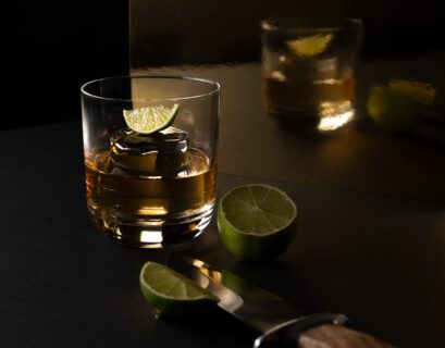 clear drinking glass with yellow liquid and sliced lime