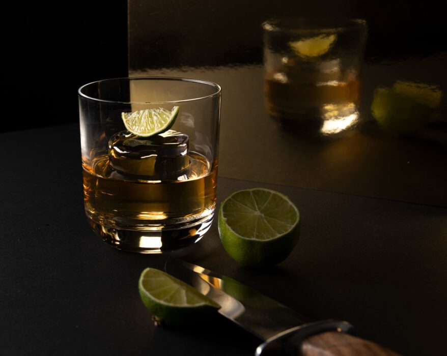 clear drinking glass with yellow liquid and sliced lime